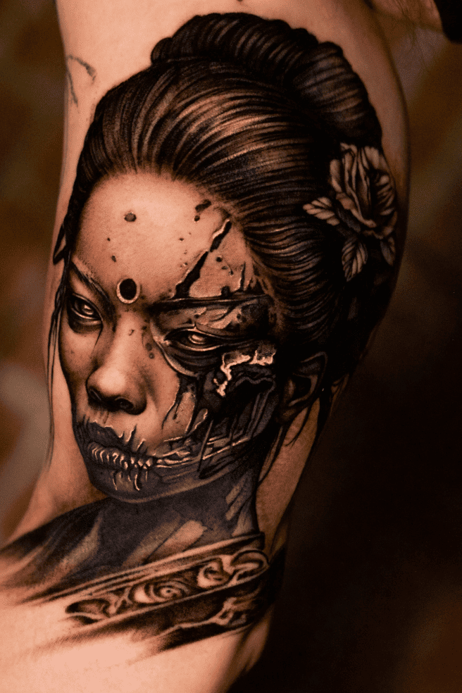 Geisha portrait with a half-decayed skull face, black and grey realism on the upper arm