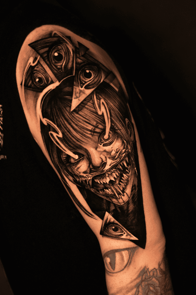 Grinning horned demon framed by triangles and floating eyes, black and grey realism upper-arm sleeve