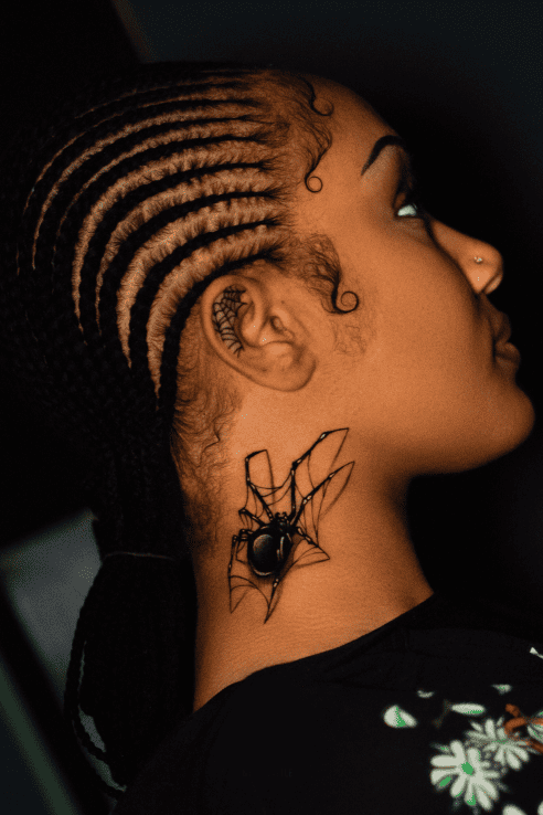 Black widow spider on a fine-line web, tattooed on the neck