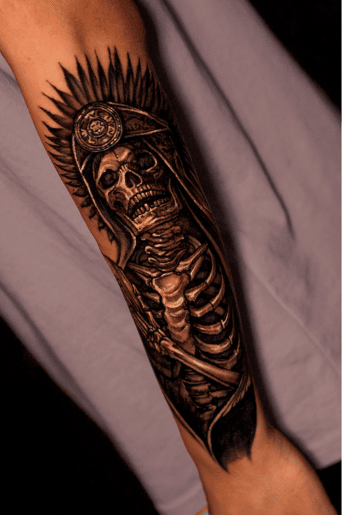 Skeleton in an Aztec feathered headdress, black and grey realism forearm sleeve