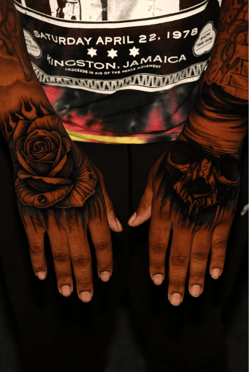 Rose and skull tattooed across the backs of both hands, black and grey realism