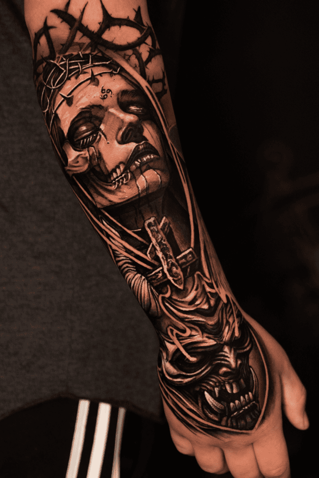 Forearm sleeve: crowned figure in a crown of thorns above a hannya mask, black and grey realism