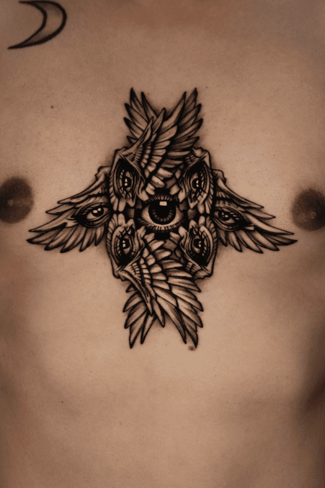 Blackwork chest piece: a cross of feathered wings filled with eyes